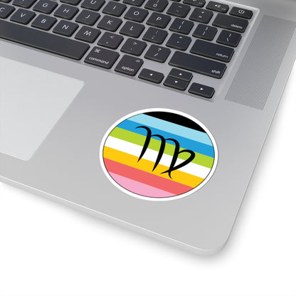 Close-up of the bottom right corner of a silver laptop featuring a 3 inch by 3 inch circular zodiac sticker with a centered Virgo glyph on a Queer pride flag style background applied to the surface.
