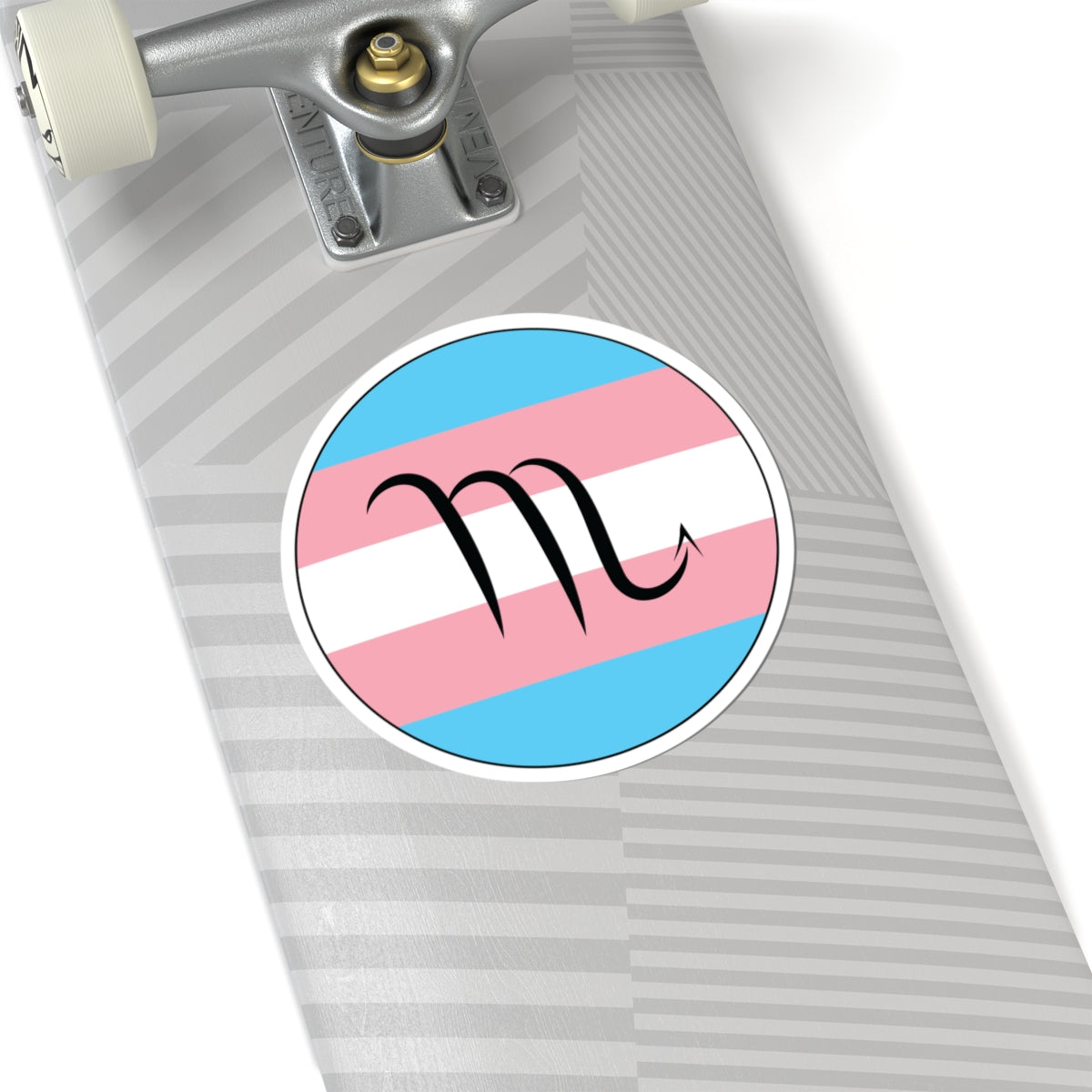 Close-up of the bottom of a silver skateboard featuring a 6 inch by 6 inch circular zodiac sticker with a centered Scorpio glyph on a Transgender pride flag style background applied to the surface.