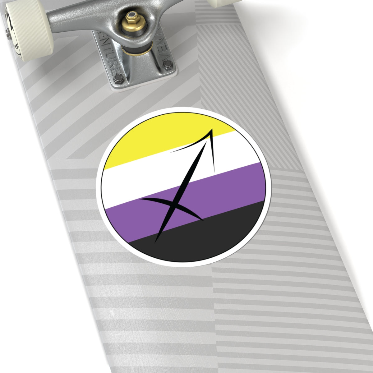 Close-up of the bottom of a silver skateboard featuring a 6 inch by 6 inch circular zodiac sticker with a centered Sagittarius glyph on an Nonbinary pride flag style background applied to the surface.