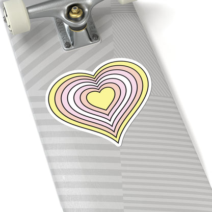 Close-up of the bottom of a silver skateboard featuring a 6 inch by 6 inch pride flag heart sticker in a Pangender flag style applied to the surface.