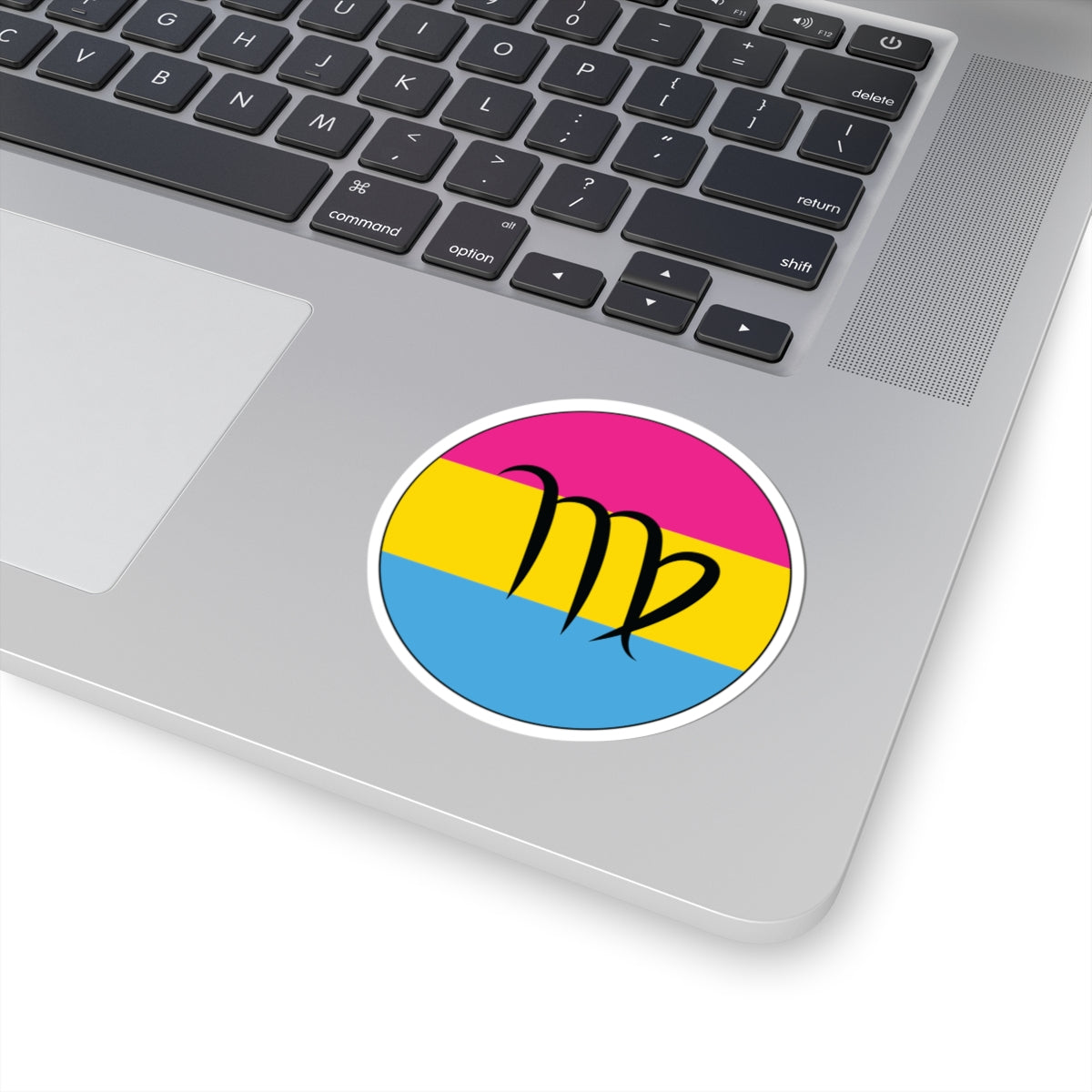 Close-up of the bottom right corner of a silver laptop featuring a 3 inch by 3 inch circular zodiac sticker with a centered Virgo glyph on a Pansexual pride flag style background applied to the surface.