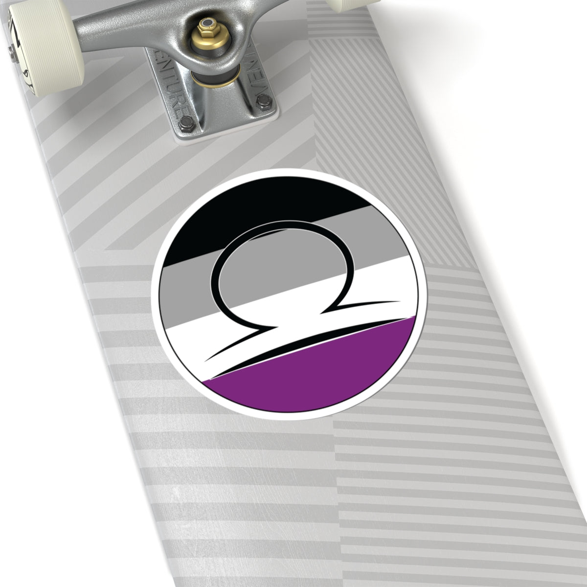 Close-up of the bottom of a silver skateboard featuring a 6 inch by 6 inch circular zodiac sticker with a centered Libra glyph on an Asexual pride flag style background applied to the surface.