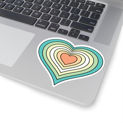 Close-up of the bottom right corner of a silver laptop featuring a 4 inch by 4 inch pride flag heart sticker in a Genderfloren flag style applied to the surface.