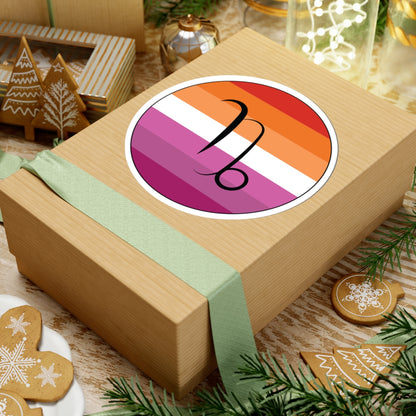 Gift box with a green ribbon on a festive background with cookies and Christmas decorations. Capricorn Lesbian pride sticker centered on the box.