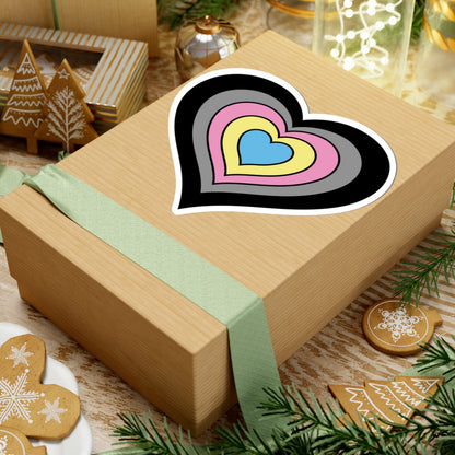 Gift box with a green ribbon on a festive background with cookies and Christmas decorations. Heart-shaped Polygender pride sticker centered on the box.