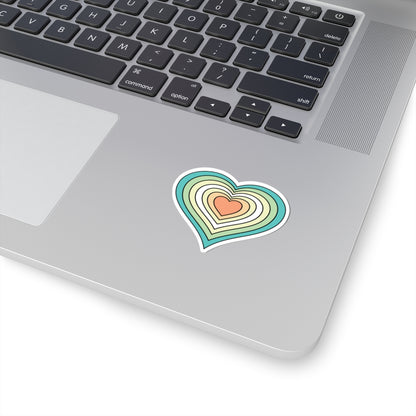 Close-up of the bottom right corner of a silver laptop featuring a 2 inch by 2 inch pride flag heart sticker in a Genderfloren flag style applied to the surface.