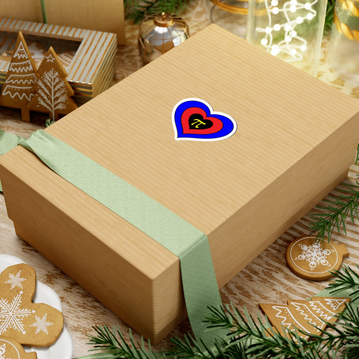 Gift box with a green ribbon on a festive background with cookies and Christmas decorations. Heart-shaped Polyamory pride sticker centered on the box.