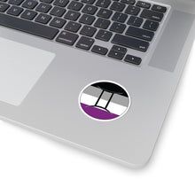Close-up of the bottom right corner of a silver laptop featuring a 2 inch by 2 inch circular zodiac sticker with a centered Gemini glyph on an Asexual pride flag style background applied to the surface.