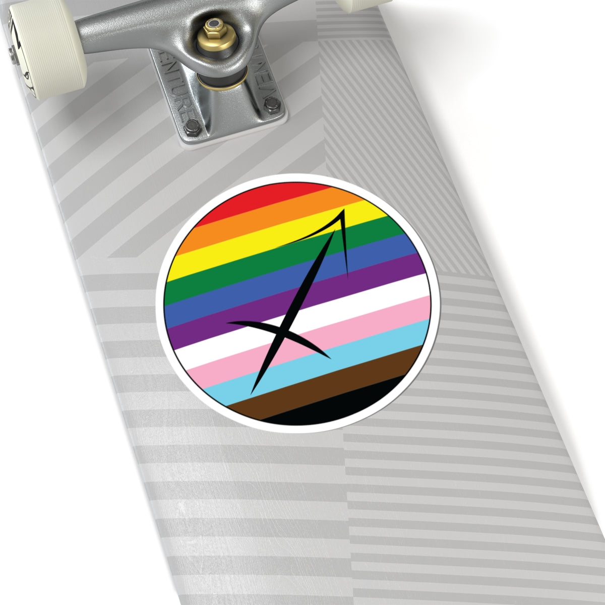Close-up of the bottom of a silver skateboard featuring a 6 inch by 6 inch circular zodiac sticker with a centered Sagittarius glyph on a progress pride flag style background applied to the surface.