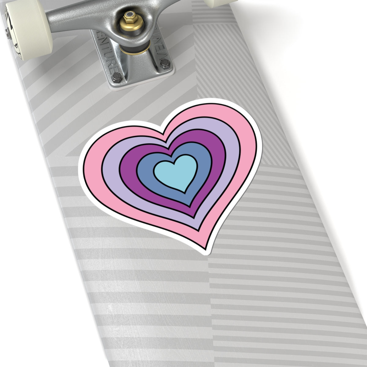 Close-up of the bottom of a silver skateboard featuring a 6 inch by 6 inch pride flag heart sticker in an Omnigender flag style applied to the surface.