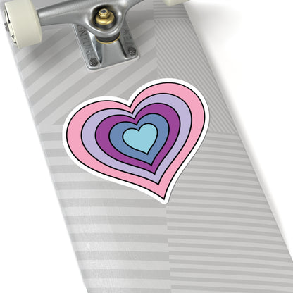 Close-up of the bottom of a silver skateboard featuring a 6 inch by 6 inch pride flag heart sticker in an Omnigender flag style applied to the surface.