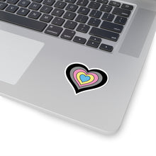 Close-up of the bottom right corner of a silver laptop featuring a 2 inch by 2 inch pride flag heart sticker in a Polygender flag style applied to the surface.