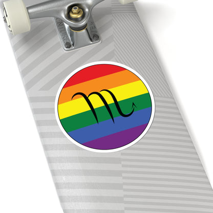 Close-up of the bottom of a silver skateboard featuring a 6 inch by 6 inch circular zodiac sticker with a centered Scorpio glyph on a Rainbow pride flag style background applied to the surface.
