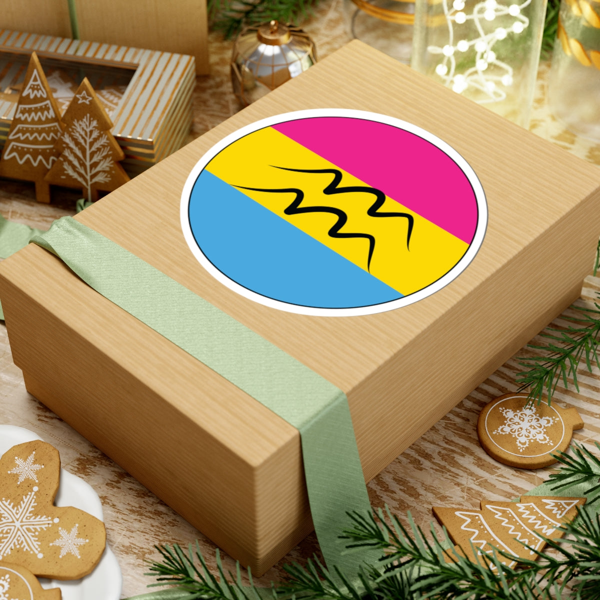 Gift box with a green ribbon on a festive background with cookies and Christmas decorations. Aquarius Pansexual pride sticker centered on the box.