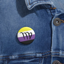 Close-up of a white circular pride button featuring the Virgo zodiac glyph centered over a nonbinary pride flag background in yellow, white, purple, and black, attached to a blue denim jacket at the right chest with the button clearly visible.