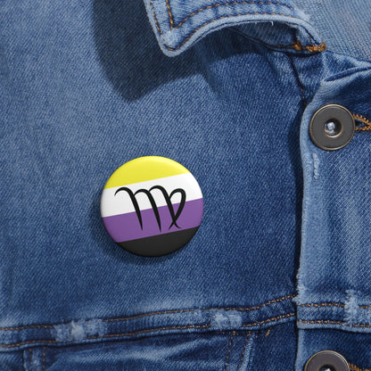 Close-up of a white circular pride button featuring the Virgo zodiac glyph centered over a nonbinary pride flag background in yellow, white, purple, and black, attached to a blue denim jacket at the right chest with the button clearly visible.