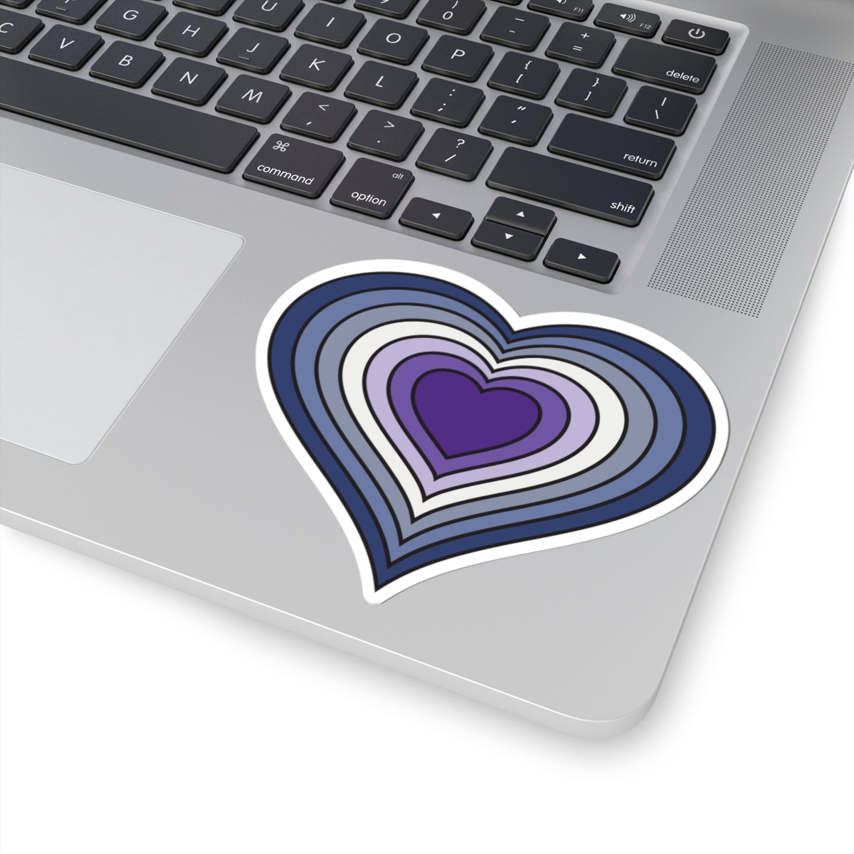 Close-up of the bottom of a silver skateboard featuring a 4 inch by 4 inch pride flag heart sticker in a purple butch pride flag style applied to the surface.