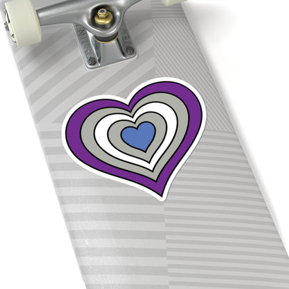 Close-up of the bottom of a silver skateboard featuring a 6 inch by 6 inch pride flag heart sticker in a Greysexual flag style applied to the surface.
