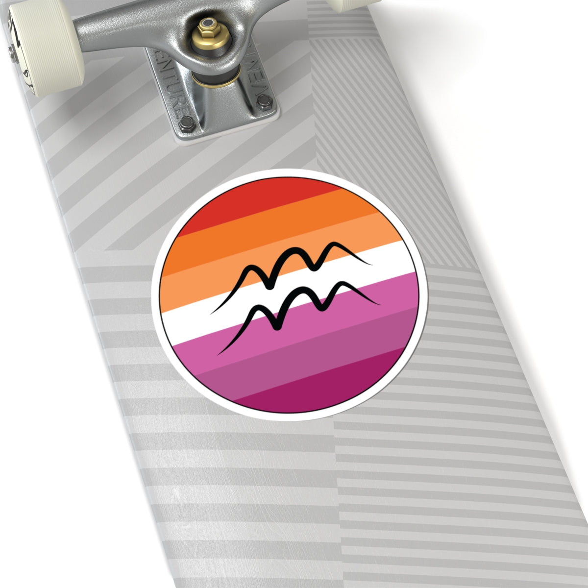 Close-up of the bottom of a silver skateboard featuring a 6 inch by 6 inch circular zodiac sticker with a centered Aquarius glyph on a Lesbian pride flag style background applied to the surface.