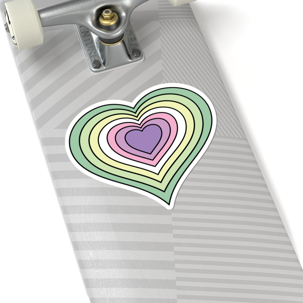 Close-up of the bottom of a silver skateboard featuring a 6 inch by 6 inch pride flag heart sticker in a Genderfae flag style applied to the surface.