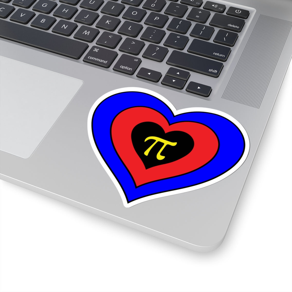 Close-up of the bottom right corner of a silver laptop featuring a 4 inch by 4 inch pride flag heart sticker in a Polyamory flag style applied to the surface.