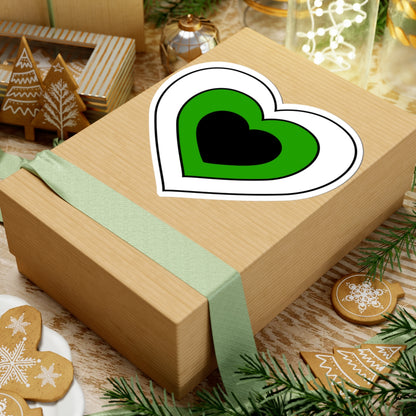 Gift box with a green ribbon on a festive background with cookies and Christmas decorations. Heart-shaped Neutrois pride sticker centered on the box.