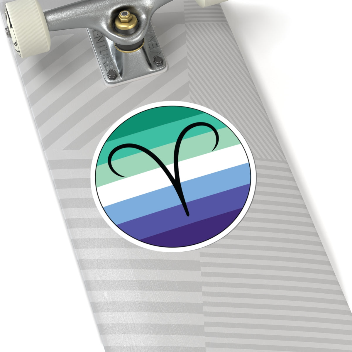 Close-up of the bottom right corner of a silver laptop featuring a 6 inch by 6 inch circular zodiac sticker with a centered Aires glyph on a Gay Men pride flag style background applied to the surface.