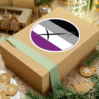 Gift box with a green ribbon on a festive background with cookies and Christmas decorations. Sagittarius Asexual pride sticker centered on the box.