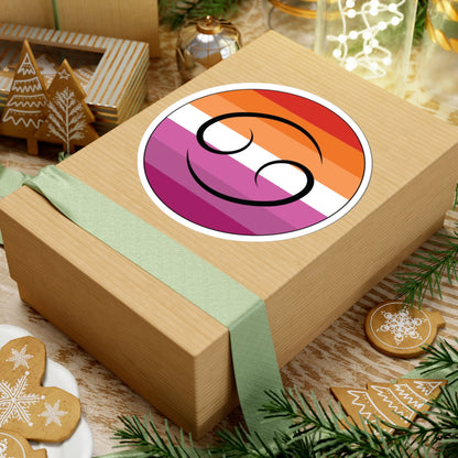 Gift box with a green ribbon on a festive background with cookies and Christmas decorations. Cancer Lesbian pride sticker centered on the box.