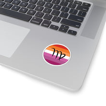 Close-up of the bottom right corner of a silver laptop featuring a 2 inch by 2 inch circular zodiac sticker with a centered Virgo glyph on a Lesbian pride flag style background applied to the surface.