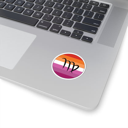 Close-up of the bottom right corner of a silver laptop featuring a 2 inch by 2 inch circular zodiac sticker with a centered Virgo glyph on a Lesbian pride flag style background applied to the surface.