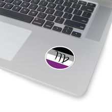 Close-up of the bottom right corner of a silver laptop featuring a 2 inch by 2 inch circular zodiac sticker with a centered Virgo glyph on an Asexual pride flag style background applied to the surface.