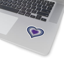Close-up of the bottom of a silver skateboard featuring a 2 inch by 2 inch pride flag heart sticker in a purple butch pride flag style applied to the surface.