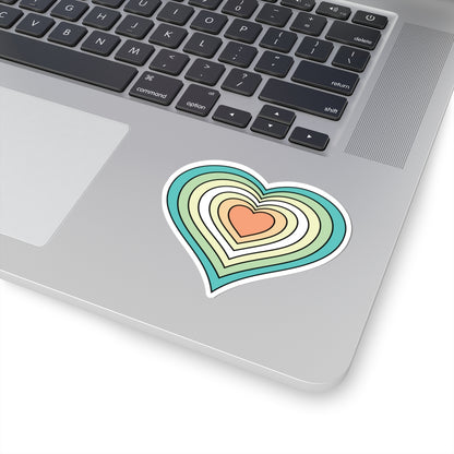Gift box with a green ribbon on a festive background with cookies and Christmas decorations. Heart-shaped Genderfloren pride sticker centered on the box.