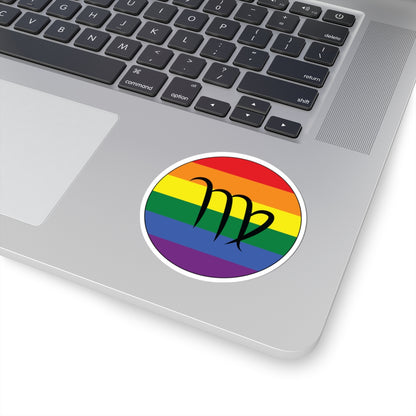 Close-up of the bottom right corner of a silver laptop featuring a 3 inch by 3 inch circular zodiac sticker with a centered Virgo glyph on a Rainbow pride flag style background applied to the surface.