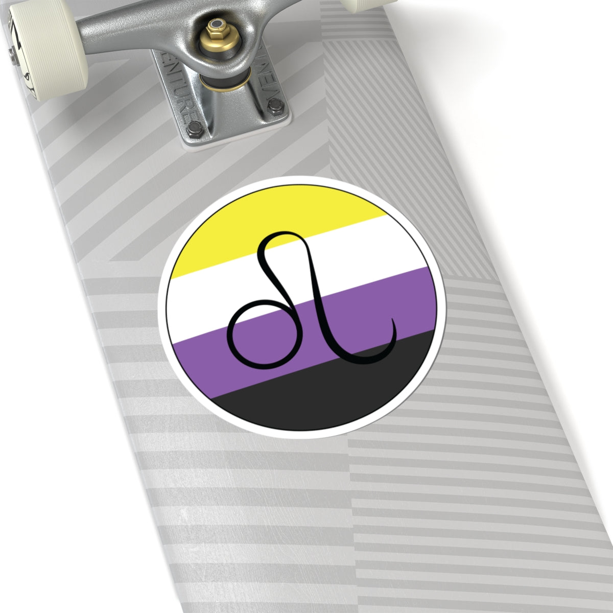 Close-up of the bottom of a silver skateboard featuring a 6 inch by 6 inch circular zodiac sticker with a centered Leo glyph on a Nonbinary pride flag style background applied to the surface.