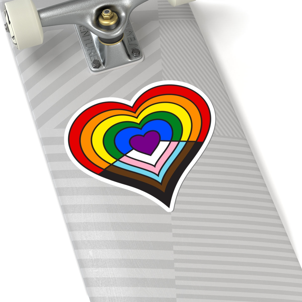 Close-up of the bottom of a silver skateboard featuring a 6 inch by 6 inch pride flag heart sticker in a Progress pride flag style applied to the surface.
