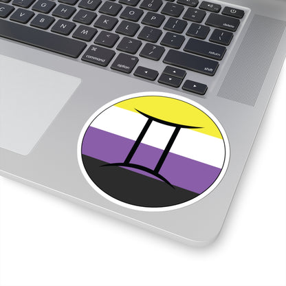 Close-up of the bottom right corner of a silver laptop featuring a 4 inch by 4 inch circular zodiac sticker with a centered Gemini glyph on a Nonbinary pride flag style background applied to the surface.