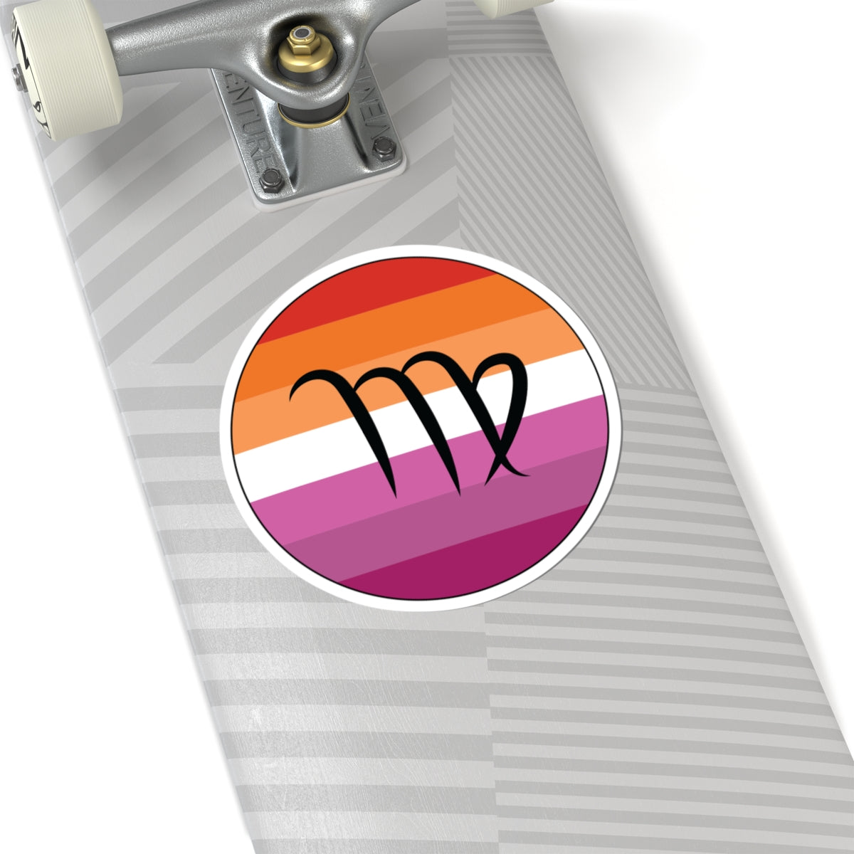 Close-up of the bottom of a silver skateboard featuring a 6 inch by 6 inch circular zodiac sticker with a centered Virgo glyph on a Lesbian pride flag style background applied to the surface.