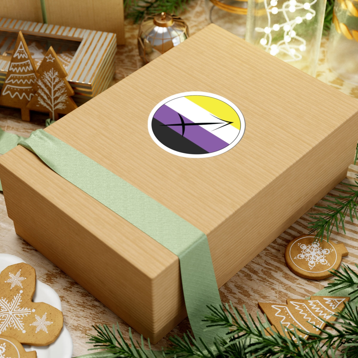 Gift box with a green ribbon on a festive background with cookies and Christmas decorations. Sagittarius Nonbinary pride sticker centered on the box.