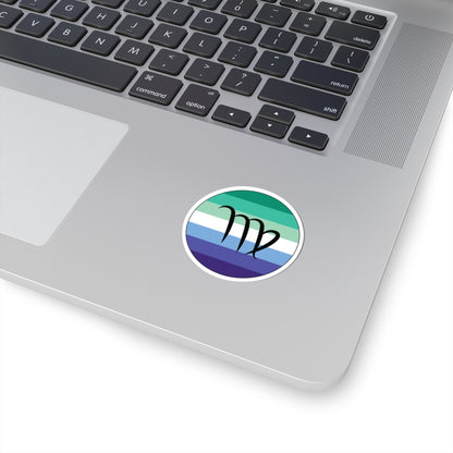 Close-up of the bottom right corner of a silver laptop featuring a 2 inch by 2 inch circular zodiac sticker with a centered Virgo glyph on a Gay Men pride flag style background applied to the surface.