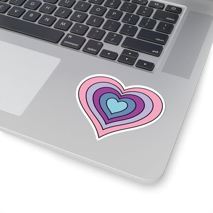 Close-up of the bottom right corner of a silver laptop featuring a 3 inch by 3 inch pride flag heart sticker in an Omnigender flag style applied to the surface.