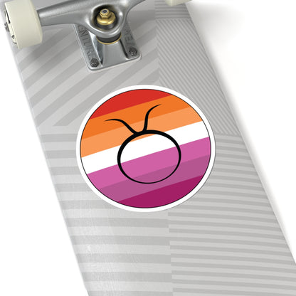 Close-up of the bottom of a silver skateboard featuring a 6 inch by 6 inch circular zodiac sticker with a centered Taurus glyph on a Lesbian pride flag style background applied to the surface.