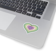 Close-up of the bottom right corner of a silver laptop featuring a 2 inch by 2 inch pride flag heart sticker in a Genderfae flag style applied to the surface.