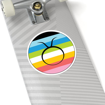 Close-up of the bottom of a silver skateboard featuring a 6 inch by 6 inch circular zodiac sticker with a centered Taurus glyph on a Queer pride flag style background applied to the surface.