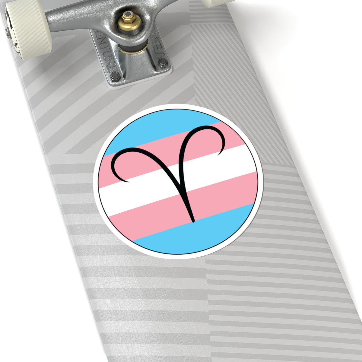 Close-up of the bottom of a silver skateboard featuring a 6 inch by 6 inch circular zodiac sticker with a centered Aires glyph on a Transgender pride flag style background applied to the surface.