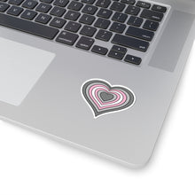 Close-up of the bottom right corner of a silver laptop featuring a 2 inch by 2 inch pride flag heart sticker in a Demigirl flag style applied to the surface.