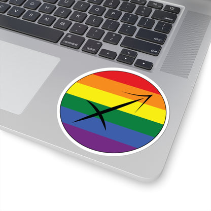 Close-up of the bottom right corner of a silver laptop featuring a 4 inch by 4 inch circular zodiac sticker with a centered Sagittarius glyph on a Rainbow pride flag style background applied to the surface.