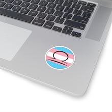 Close-up of the bottom right corner of a silver laptop featuring a 2 inch by 2 inch circular zodiac sticker with a centered Libra glyph on a Transgender pride flag style background applied to the surface.
