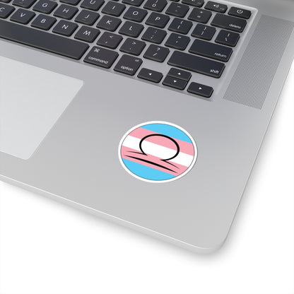 Close-up of the bottom right corner of a silver laptop featuring a 2 inch by 2 inch circular zodiac sticker with a centered Libra glyph on a Transgender pride flag style background applied to the surface.